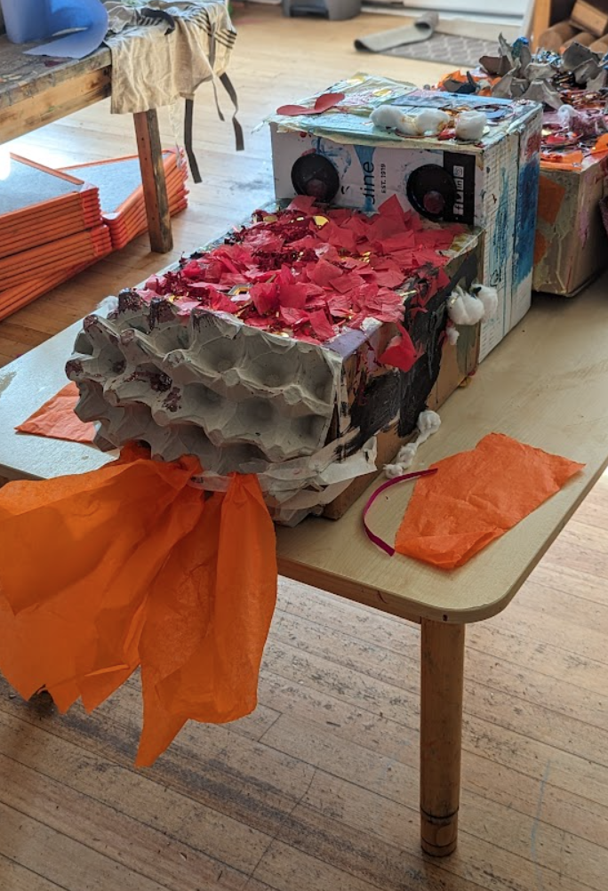 A cardboard box with red and white paper on a table
Description automatically generated