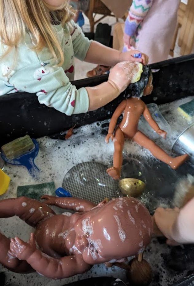 A child washing dolls in a sink
Description automatically generated